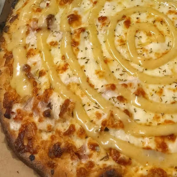 Close-up of a Freshieez pizza with melted cheese, herbs, and a spiral of sauce.
