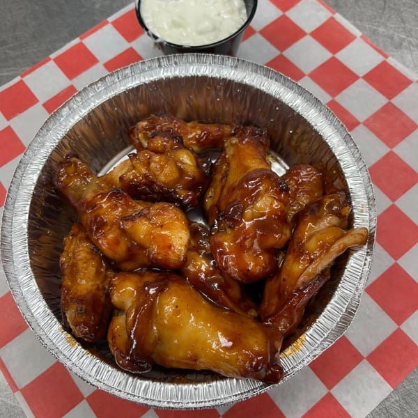 Freshieez BBQ chicken wings in a foil container with a side of ranch dressing.