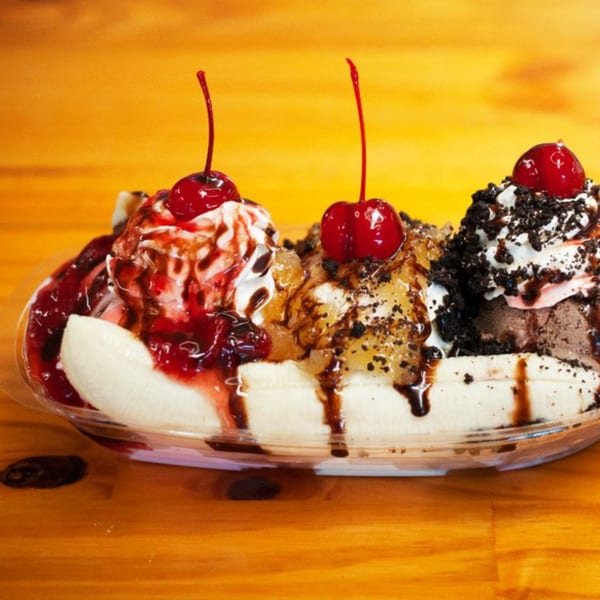 A banana split with three scoops of ice cream, whipped cream, cherries, and chocolate syrup.